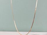 un gros plan d'un collier en or posé sur un comptoir en marbre