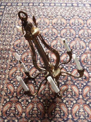 an antique brass chandelier with five lights on a blue carpet