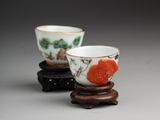 deux petites tasses ornées de motifs, posées sur un support en bois