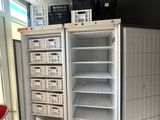 an empty refrigerator in the corner of a room with baskets on top of it