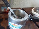 a silver pot with a spoon in it sitting on a table