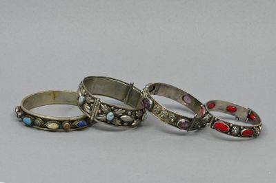 three silver rings with red and blue stones on them on a white surface