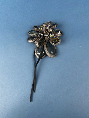an image of a silver flower brooch on a blue background