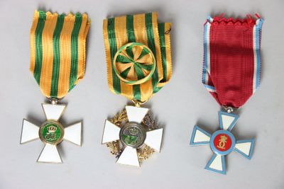 three medals and a cross on a white surface