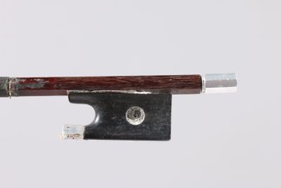 un gros plan d'un archet de violon posé sur une surface blanche