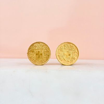 a pair of gold coins sitting on top of a white surface