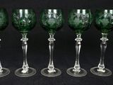 six green wine glasses lined up in a row on a black background