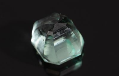 un gros plan d'un quartz vert posé sur une surface noire