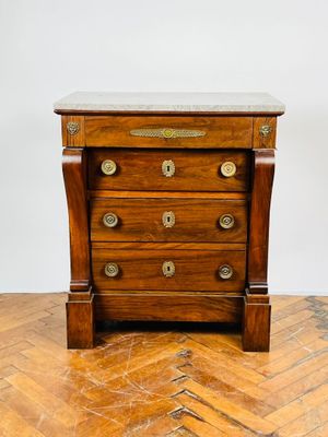 une vieille commode en bois avec un plateau en marbre, posée sur un sol en caillebotis