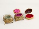 three gold and pink jewelry boxes sitting next to each other on a white surface
