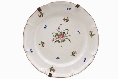 EST Assiette en faïence émaillée polychrome à décor floral.