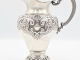 an antique silver plated pitcher on a stand with a handle