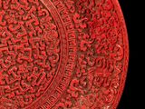 a red plate with a design on it on a black background