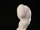 une sculpture blanche posée sur un socle noir, avec un fond noir