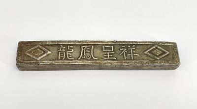 a silver bar with chinese writing on it sitting on a white surface