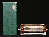 un livre vert et un rouleau métallique posés sur une surface noire