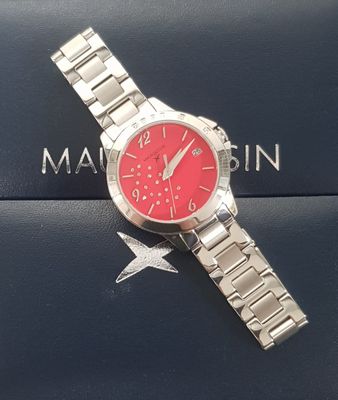 silver watch with red face on a blue box with a star on it