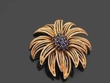 broche en forme de fleur en or et saphir sur un fond noir