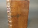 an old leather book sitting on top of a table next to a gray wall