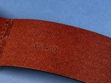 the brown leather belt is laying on a blue surface