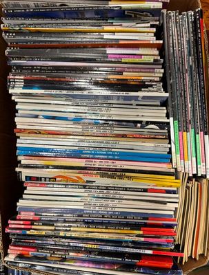 un grand nombre de DVD dans une boîte en carton posée sur le sol