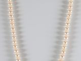 a white pearl necklace with a gold clasp on a mannequin
