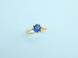 a close up of a blue sapphire ring on a white surface