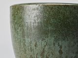 a close up of a green bowl on a white surface