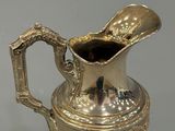 an antique silver plated pitcher with a handle on a stand