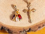 a close up of a cross and a ladybug pendant on a piece of wood