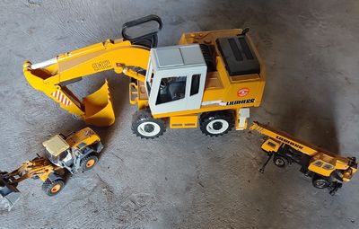 un engin de chantier miniature et un camion miniature posés par terre