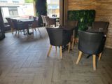 tables and chairs in a restaurant with a plant on the wall