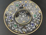 a black plate with gold and blue flowers on it