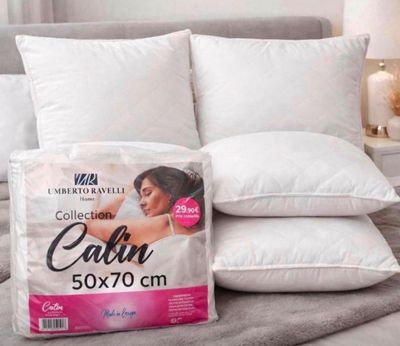 trois oreillers sur un lit, avec un oreiller posé dessus