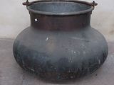 a large metal pot sitting on the ground near a wall
