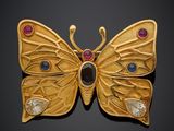 un gros plan sur une broche en forme de papillon en or ornée de pierres multicolores