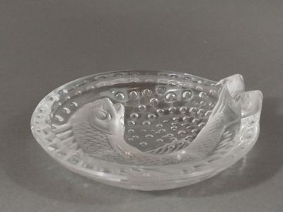 un saladier en verre orné de deux poissons, posé sur une table
