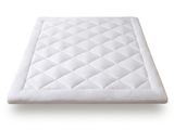Le surmatelas est en coton blanc et est doté d'une housse matelassée