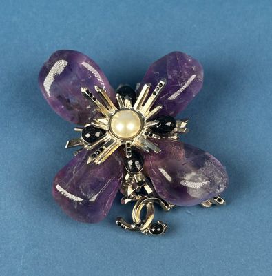 an image of a purple flower brooch with a pearl center