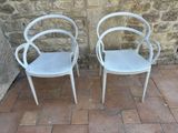 two white chairs sitting next to each other on a brick floor