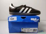 Des chaussures adidas Superstar noires et blanches posées sur une boîte bleue