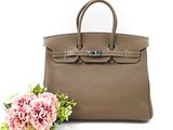 un gros plan sur un sac à main et des fleurs posés sur une surface blanche