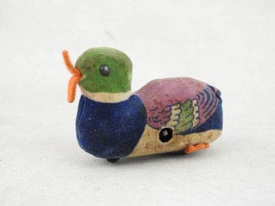 un petit oiseau en peluche posé sur une surface blanche