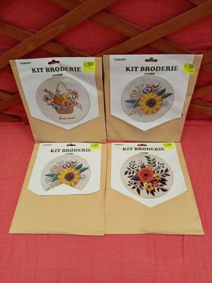 four cross stitch kits with sunflowers on them sitting on a bed