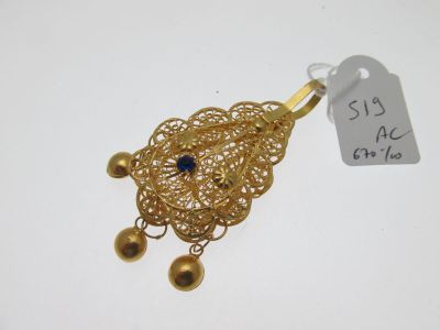 a close up of a gold necklace with a blue stone on it