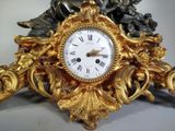 a gold clock with a statue on top of it