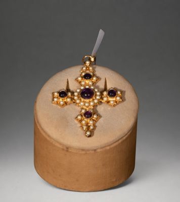 gold and amethorate cross with amethorate stones on top of a wooden box