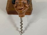 a bottle opener with a face on it and a cork opener attached to it
