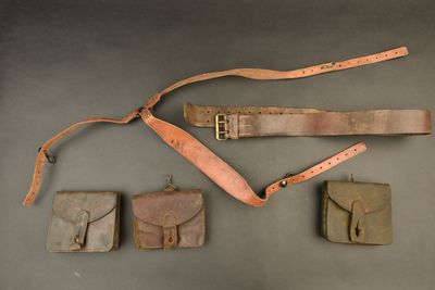several items are laid out on a table, including a belt, a wallet, and a knife