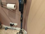 a picture of a bathroom with a vacuum and toilet paper dispenser